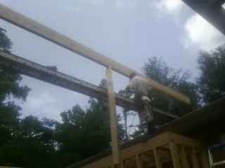 Carpenter setting a ridge beam over a new addition frame — Ice Dam Removal by Roofing Brothers in Haynesville