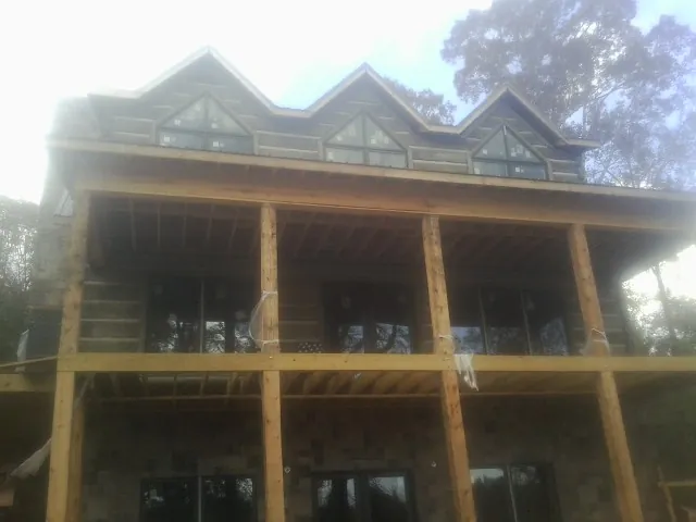 Dormers and porch framing on a large log home under construction — Roof Coating work by our crew in Haynesville