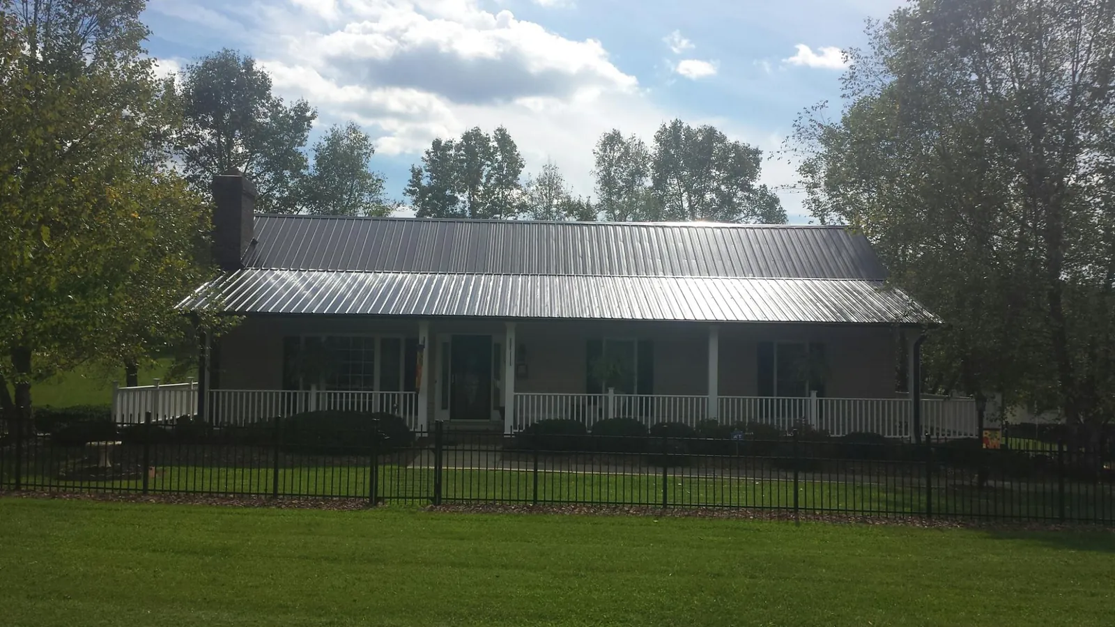 Gray metal roof on a brick ranch with a full width front porch — Gutter Guard Installation work by our crew in Haynesville