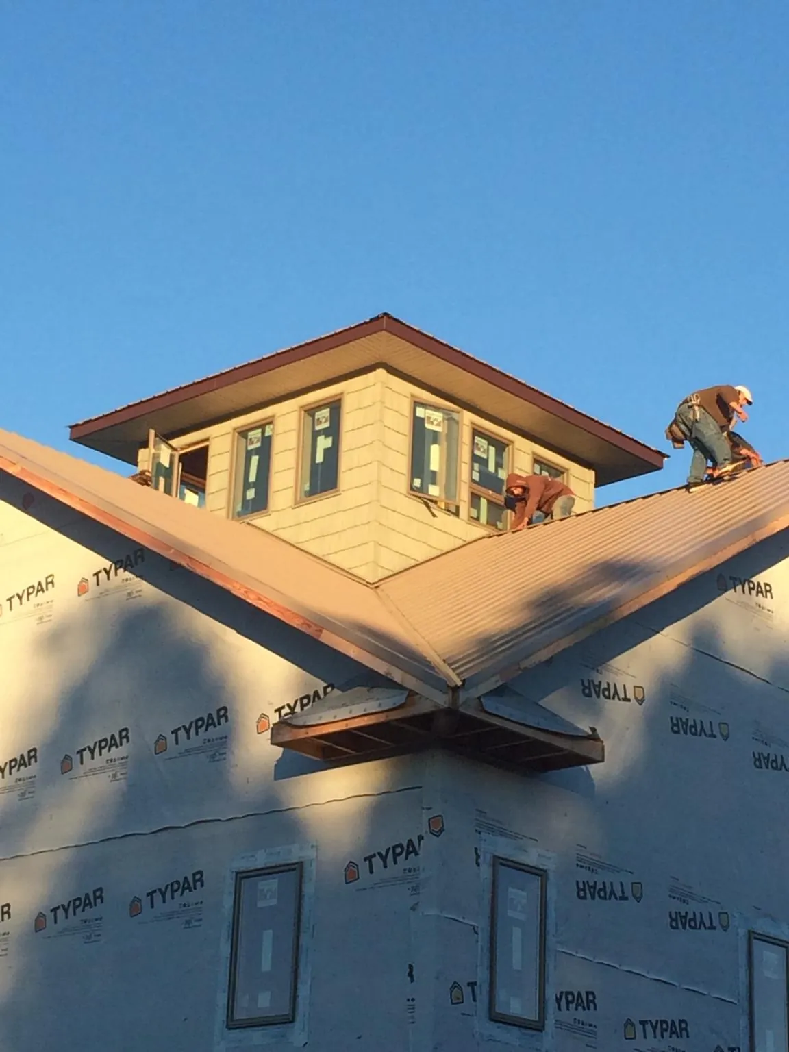 Roofers working around a rooftop cupola on a new metal roof at sunset — Roof Waterproofing in Haynesville by Roofing Brothers